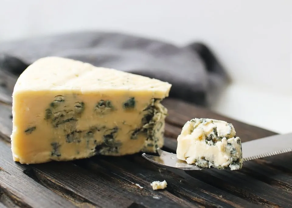 A wedge of cured blue cheese on a wooden board