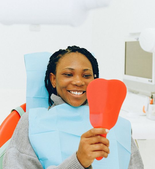 A smiling patient looking in a mirror in a bright dental clinic