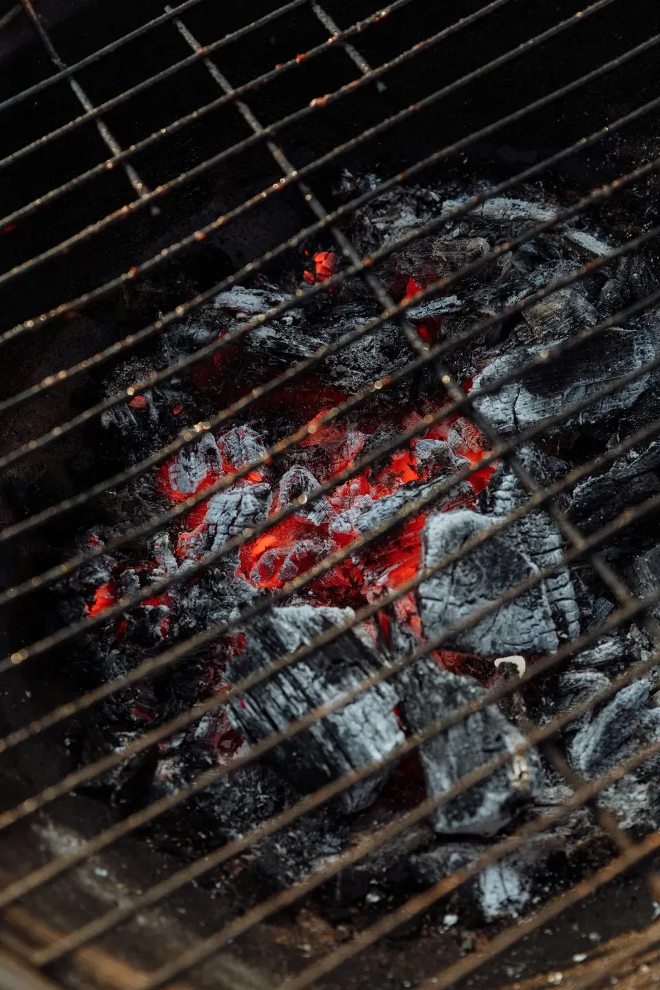 Glowing embers under a grill grate